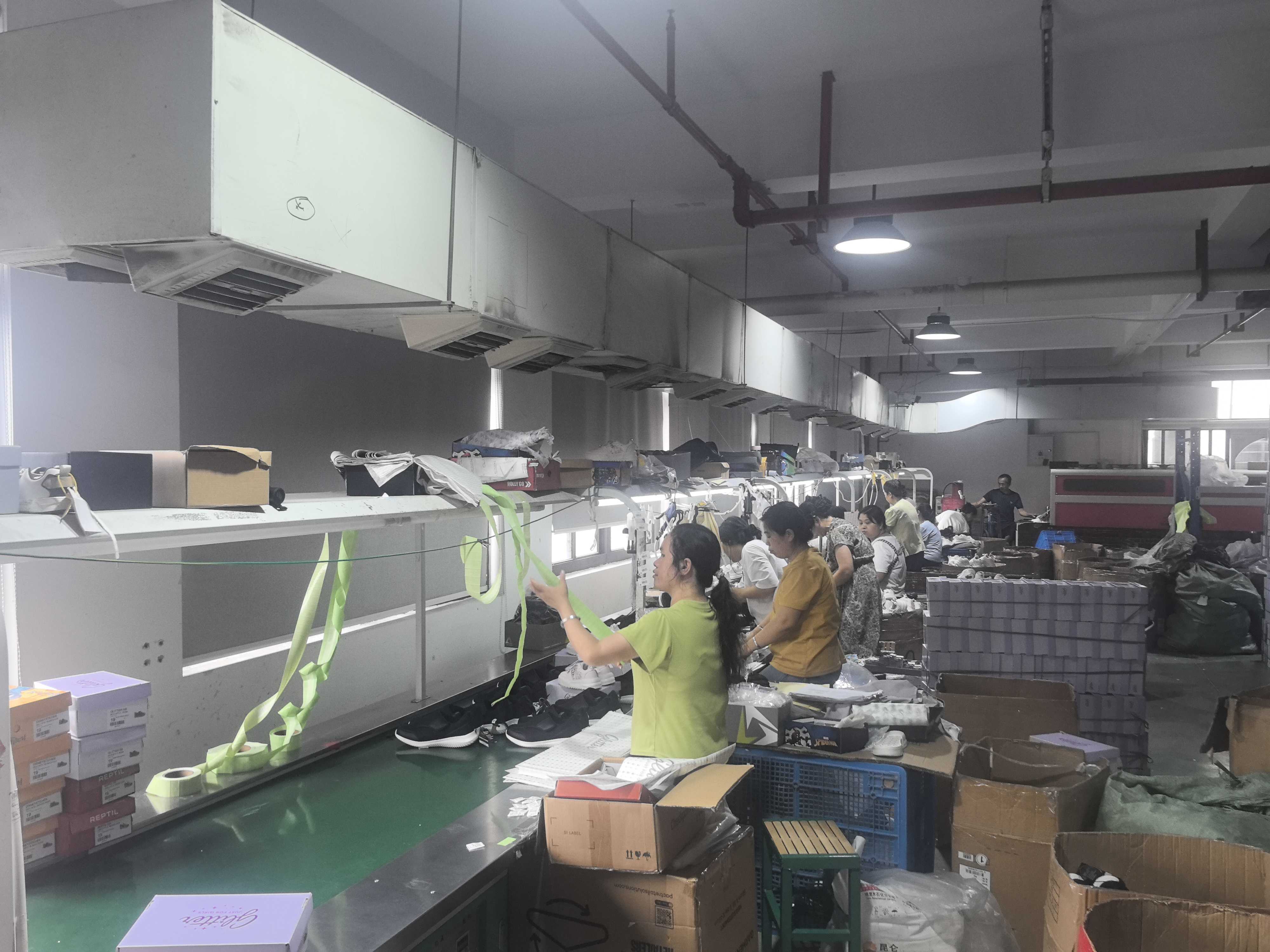 Finishing and packing area with workers preparing shoes and shoe boxes for shipment